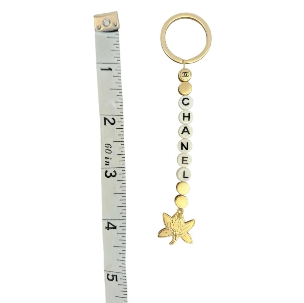 NIB CHANEL Sublimage Gold & White Beaded Keychain with Flower Charm
